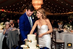 Newlyweds share joyful cake-cutting moment at Castle Hill Inn, Newport, RI A newlywed couple shares a celebratory moment as they cut into their wedding cake at Castle Hill Inn in Newport, RI.